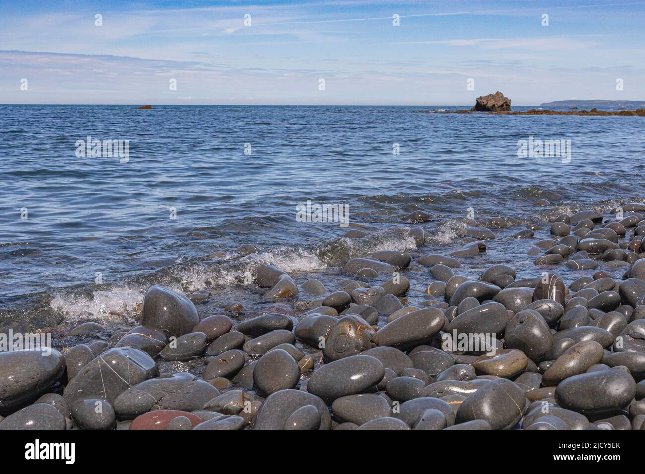 Scenic Sea View of Greencliff Beach, With Wet Pebbles, Exposed Rocks and Coastal View Towards Croyde at Mid Tide: Greencliff, Near Bideford Stock Photo