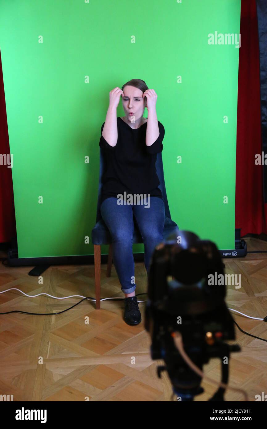 Cracow. Krakow. Poland. Female sign language interpreter works in front of the camera with the greenbox background behind her. Stock Photo