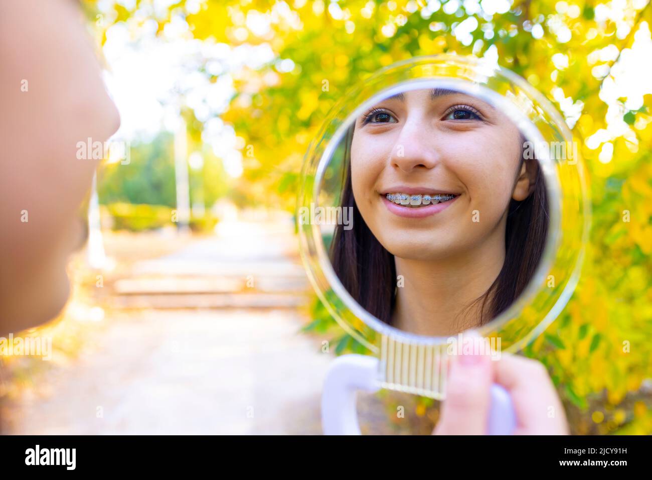 Caucasian girl looking in mirror outside Stock Photo