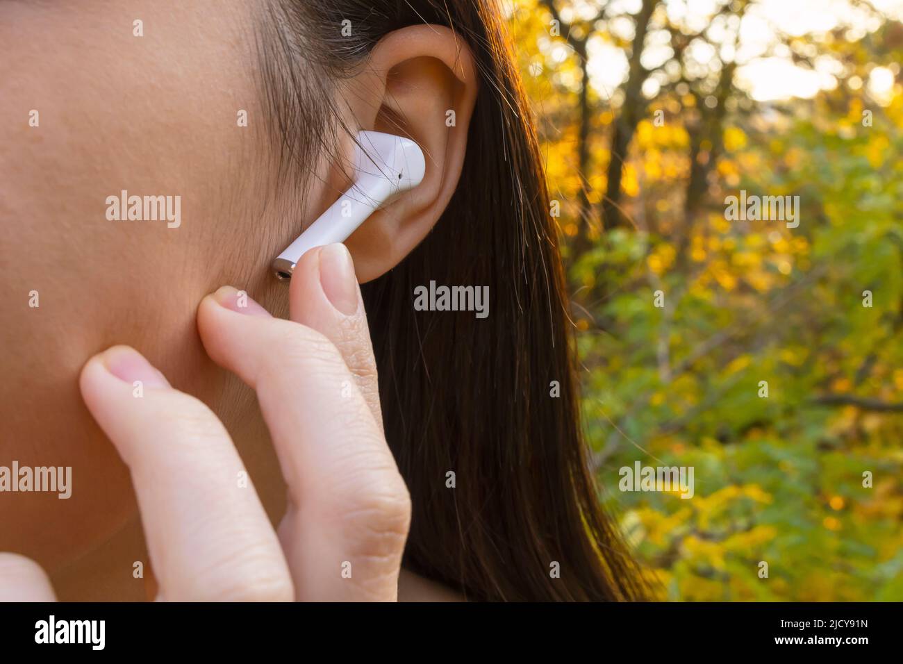 Close up of a smiling pretty young girl with wireless earphones outside Stock Photo