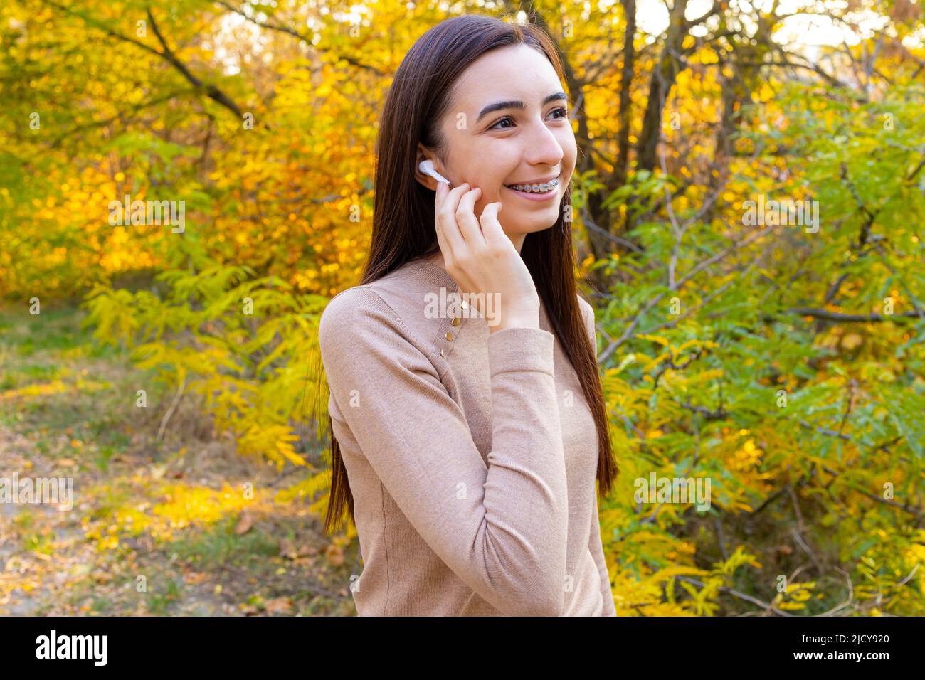 Close up of a smiling pretty young girl with wireless earphones outside Stock Photo