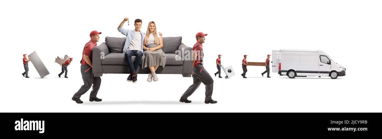 Workers from a removal company carrying a young couple sitting on a gray sofa and holding a house key isolated on white background Stock Photo