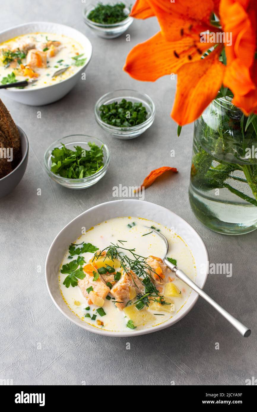 Norwegian salmon red fish soup with vegetables, herbs and cream, top view on the dining table Stock Photo