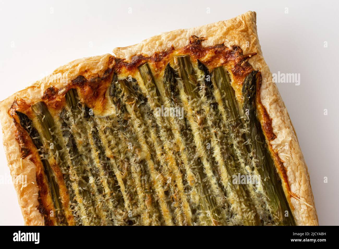Baked puff pastry pie with cheese and asparagus on a white background, top view, copy space Stock Photo