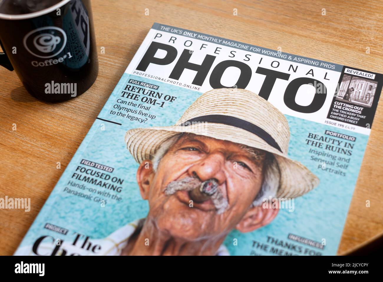 The image shows a recent copy of Professional Photo magazine, lying on a coffee No.1 cafe table, with a cup of coffee having just been purchased Stock Photo