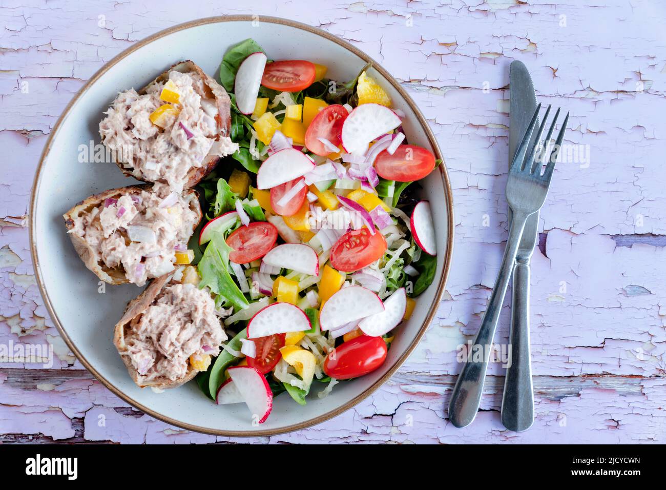 A tinned tuna salad served in a bowl. The tuna is served in empty baked potato skins with a fresh green leaf salad. A healthy keto friendly meal Stock Photo