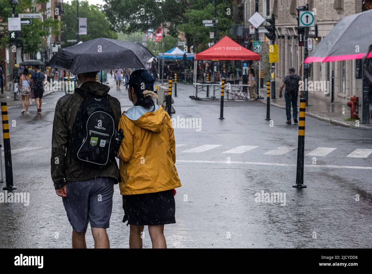 Montreal, CA - 12 June 2022: People on Mont-Royal Avenue holding umbrella during rain and storm Stock Photo