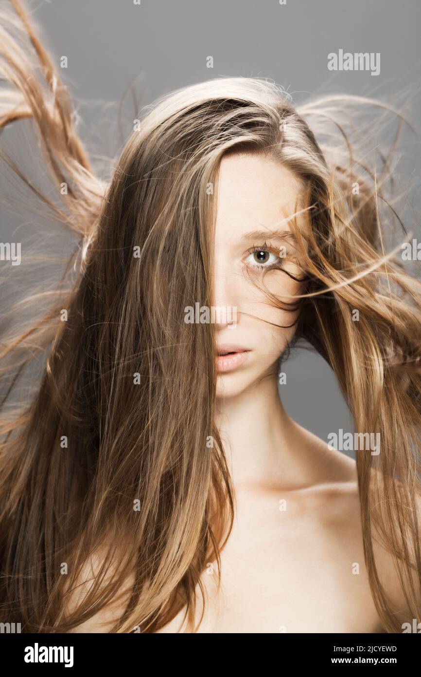 girl with flowing hair in the air studio portrait against gray