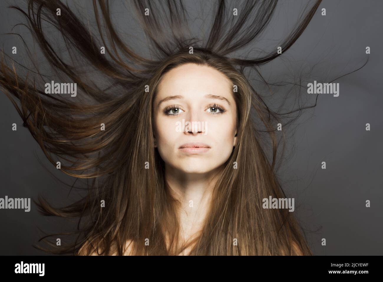 girl with flowing hair in the air studio portrait against gray