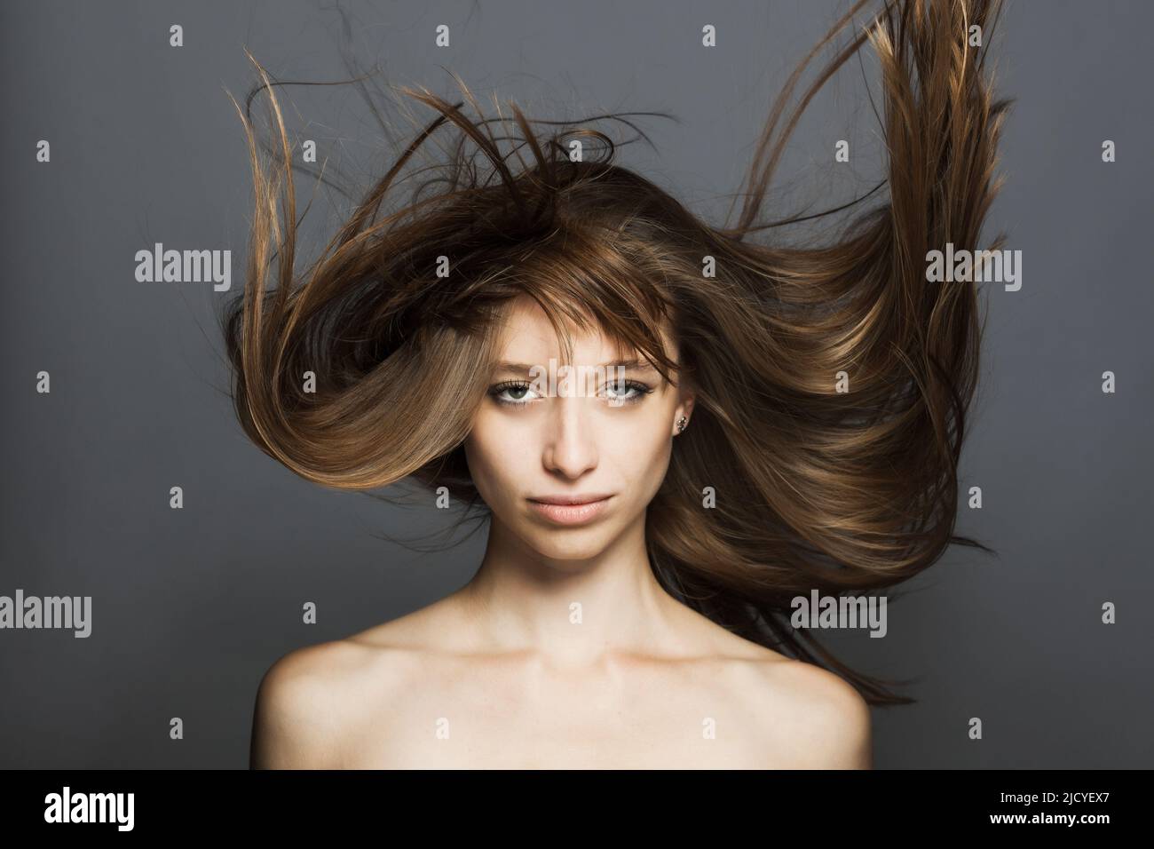girl with flowing hair in the air studio portrait against gray