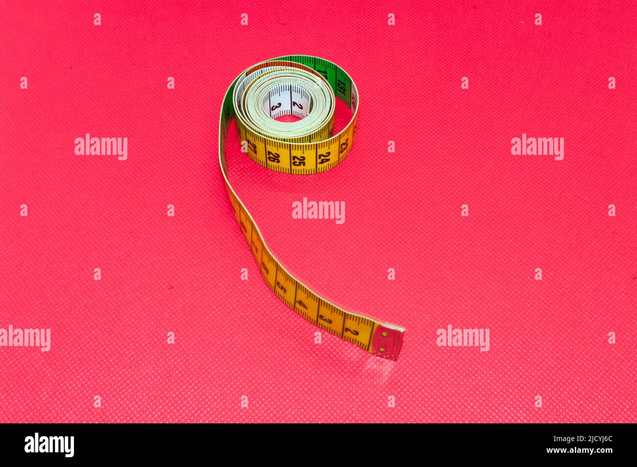 Iconic picture measure: flexible tailor's tape measure, isolated against red background Stock Photo