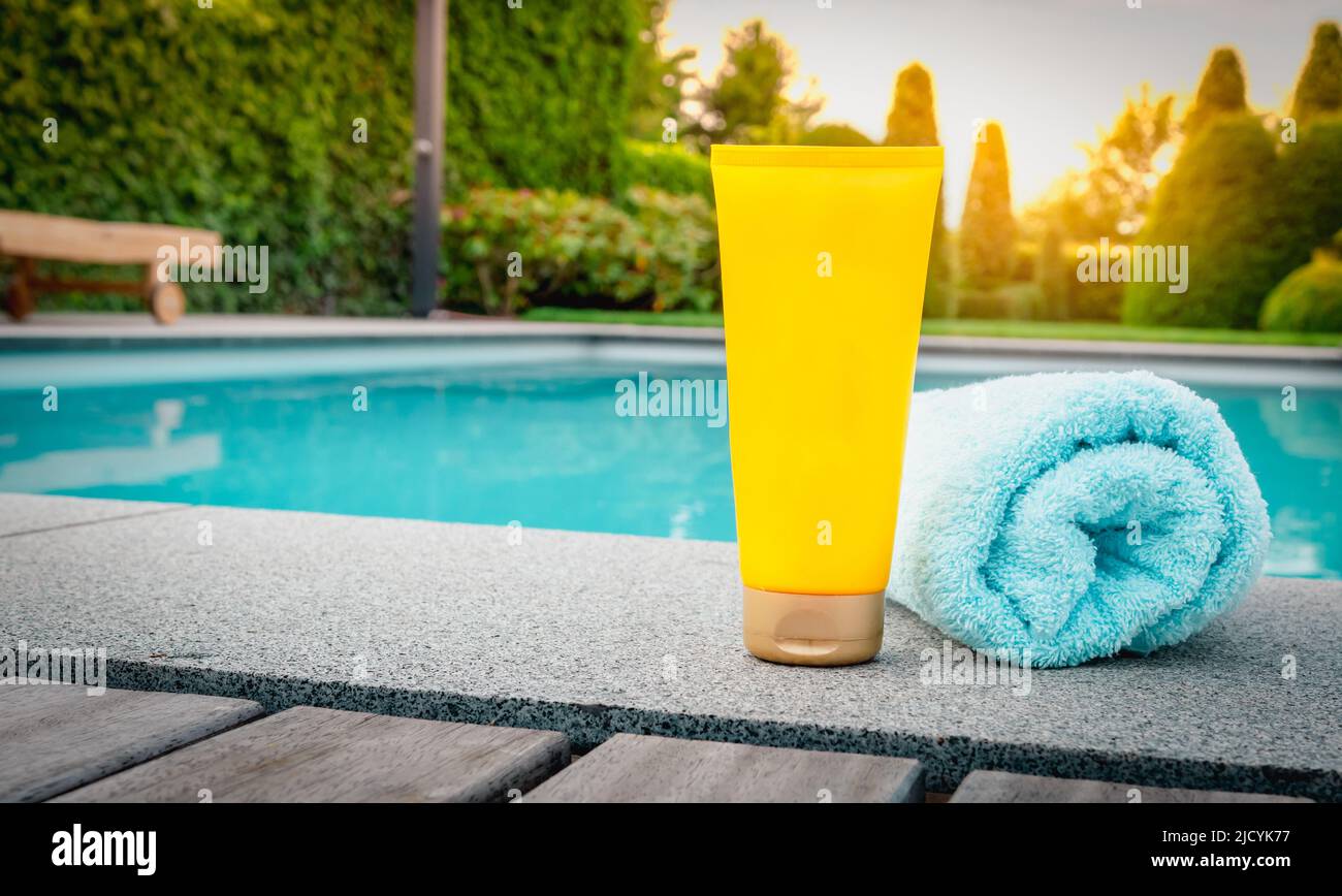 Skin care and protection against harmful sun rays. Yellow tube of sunscreen at the swimming pool. Stock Photo
