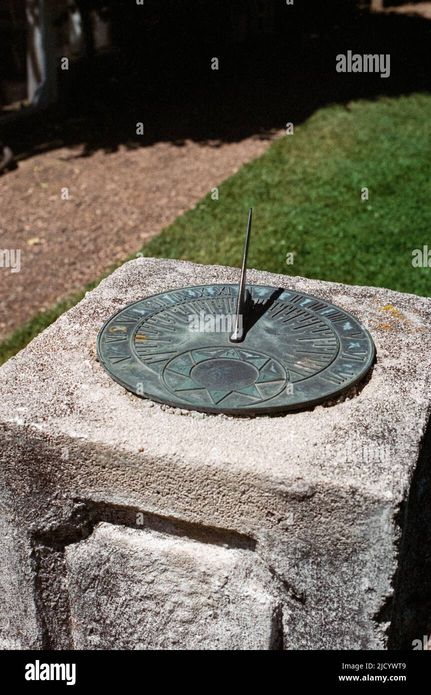 Brass sundial mounted on a decorative concrete base in the garden at