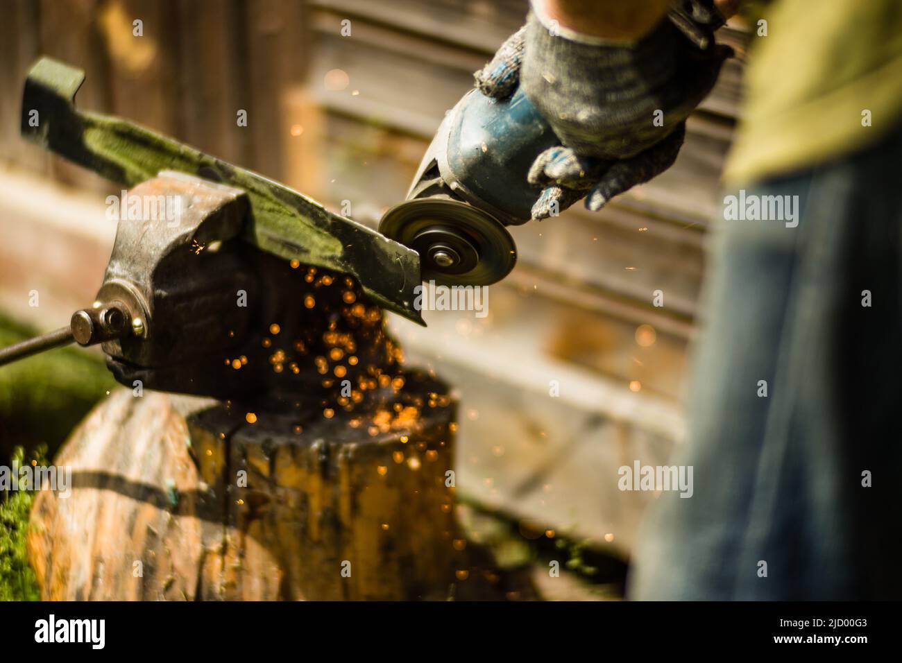 Man working with grinder saw, close up view on tool. Electric saw and hands of worker with sparks. Worker cutting metal with grinder. Stock Photo