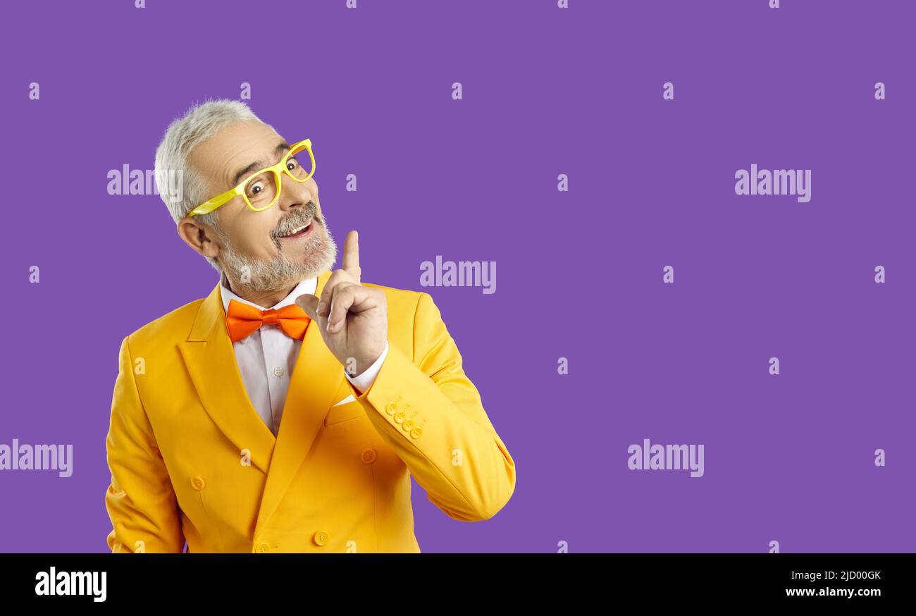Great idea. Cheerful middle aged caucasian man pointing his finger up with inspiration, yellow background. Space for your advertisement. Stock Photo
