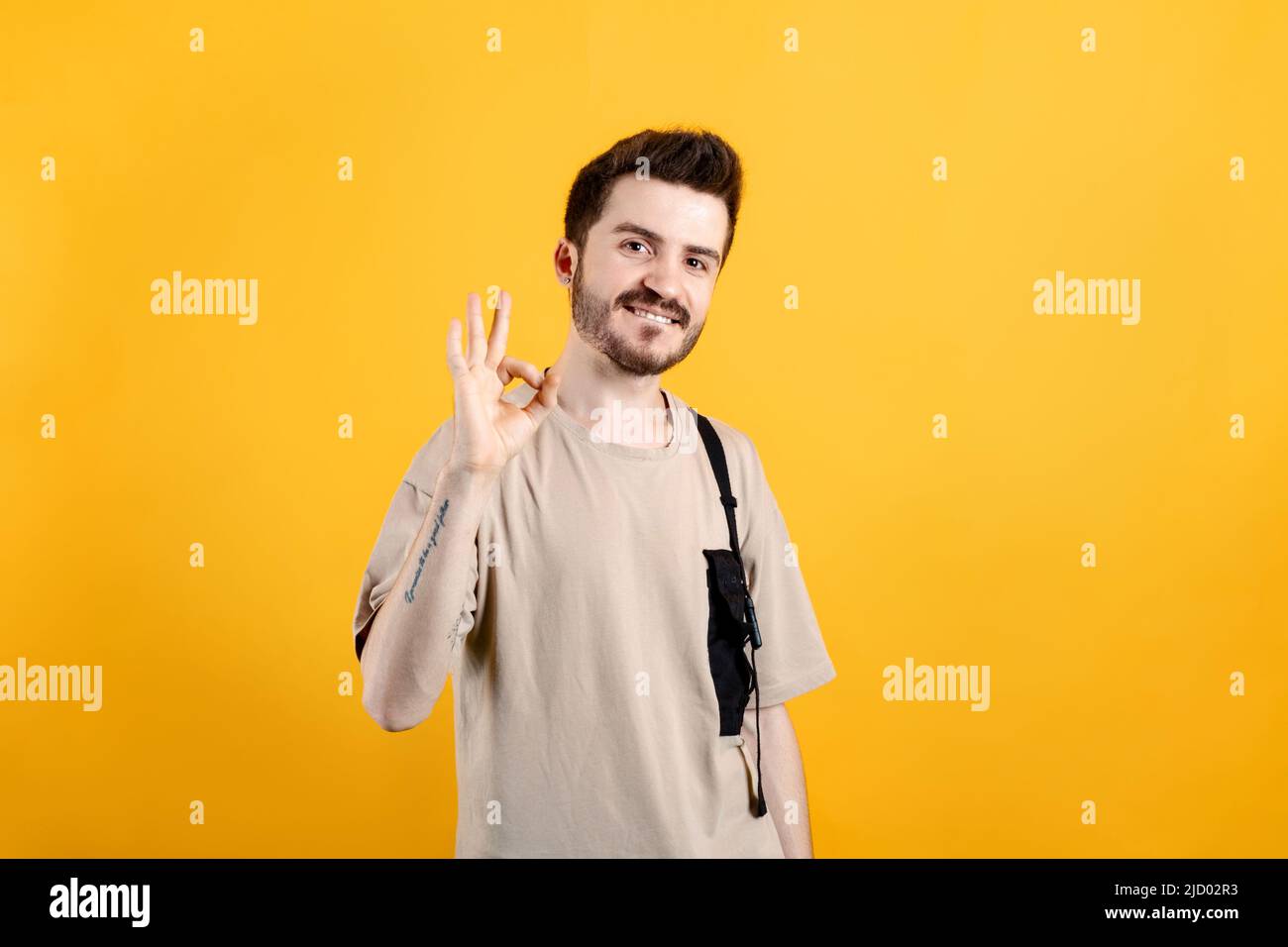 Happy casual man wearing t-shirt posing isolated over yellow background ...