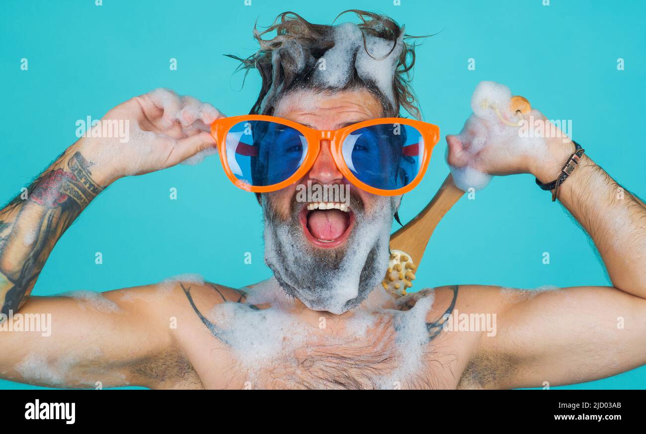 Happy man in shower. Bearded guy washing with moisturizing gel and body brush. Morning routine Stock Photo