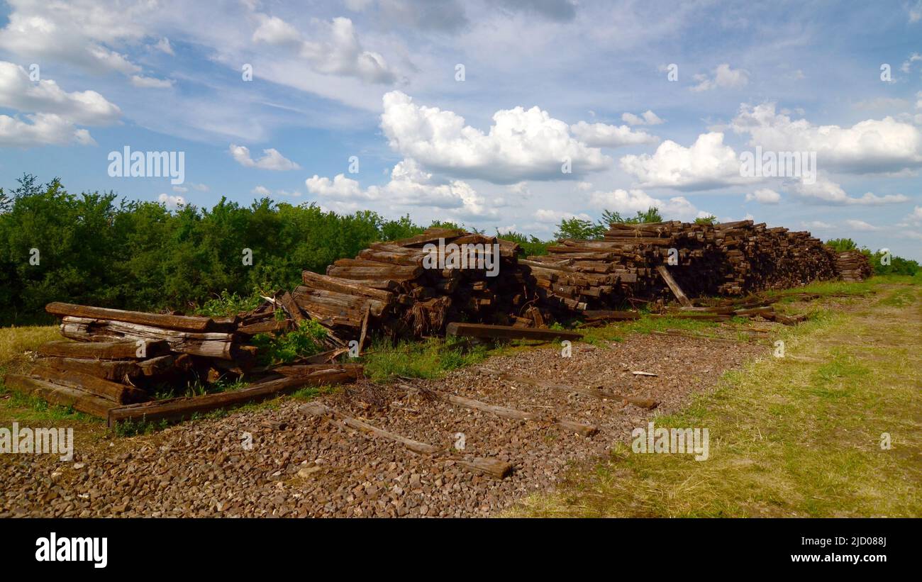 Larger piles of stacked used wooden railway sleepers. Wooden sleepers are better than other railway sleepers at absorbing the pressure. Stock Photo