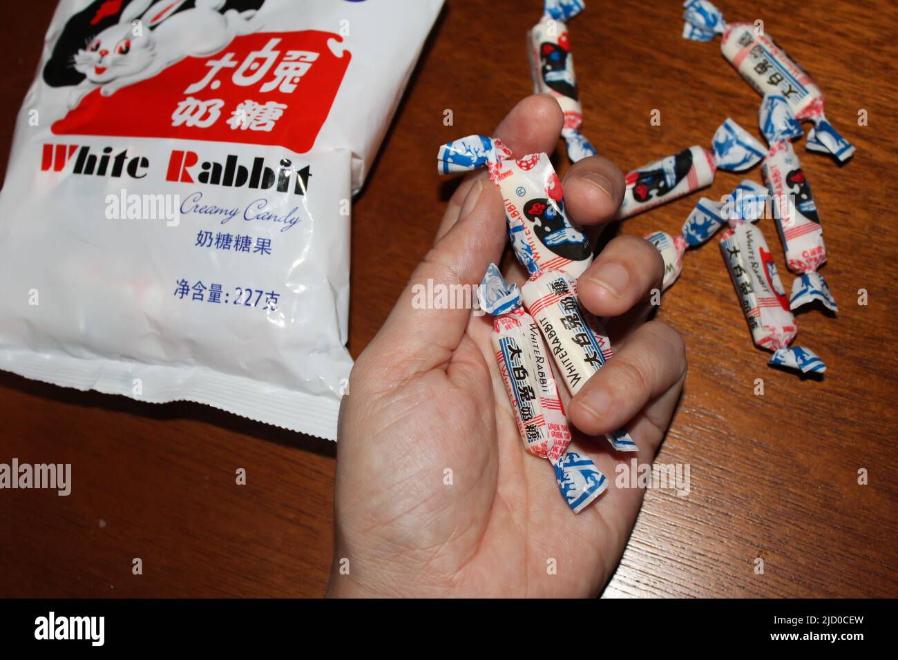 Person holding several candies of the White Rabbit Creamy Candy. This is a brand of milk candy manufactured by Shanghai Guan Sheng Yuan Food, Ltd., in Stock Photo