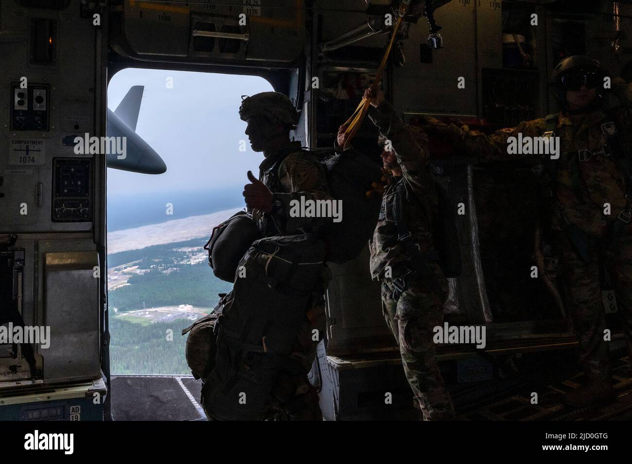 U.S. Army Sgt. 1st Class Charlie Arrendale, gives a thumbs-up signal prior to the paratroopers jumping out of a C-17 Globemaster III from the 176th Airlift Squadron, Joint Base Elmendorf-Richardson, Alaska over Allen Army Airfield, Fort Greely, June 15, 2022. RF-A provides realistic combat training by integrating joint, coalition and multilateral forces into simulated forward operating bases. The paratroopers and Arrendale are assigned to the 2nd Infantry Brigade Combat Team (Airborne), 11th Airborne Division. (U.S. Air Force photo by Sheila deVera) Stock Photo