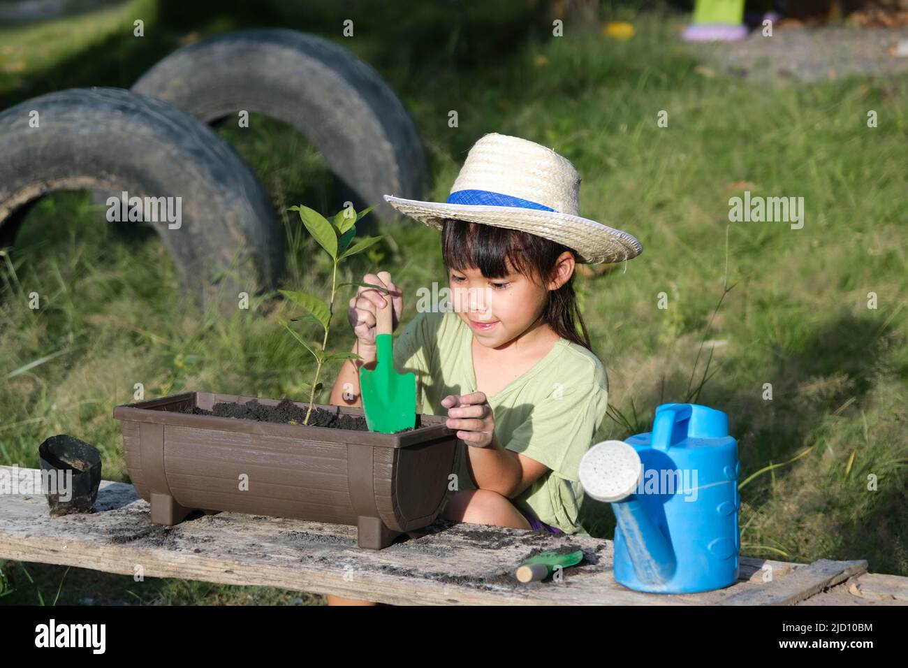 Little girl wearing a hat helps her mother in the garden, a little