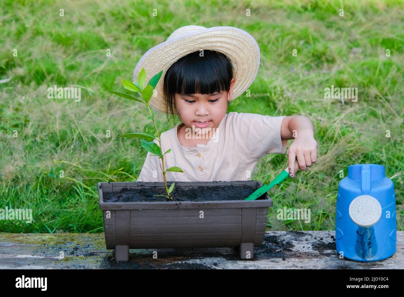 Little girl wearing a hat helps her mother in the garden, a little