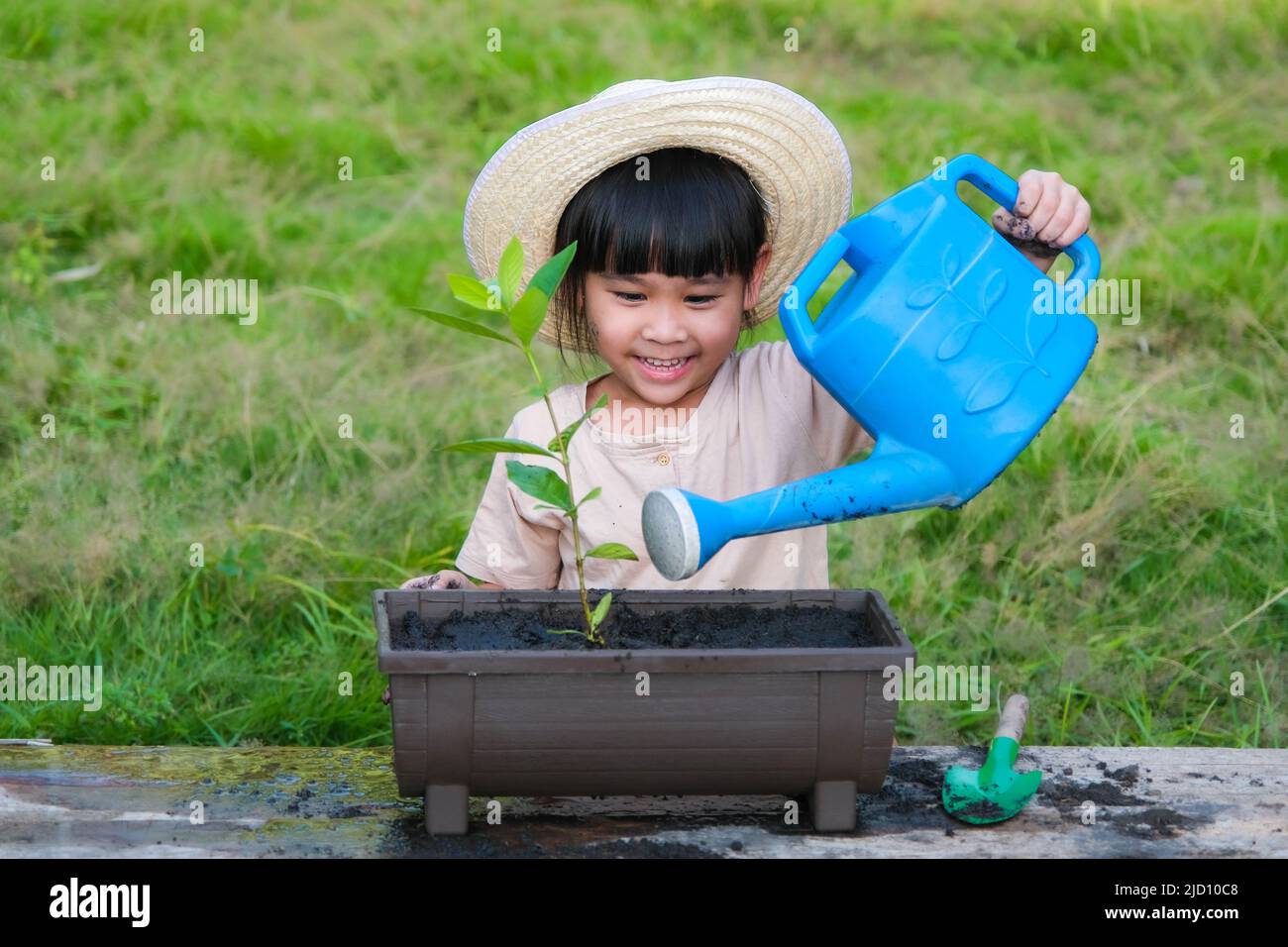 Little girl wearing a hat helps her mother in the garden, a little