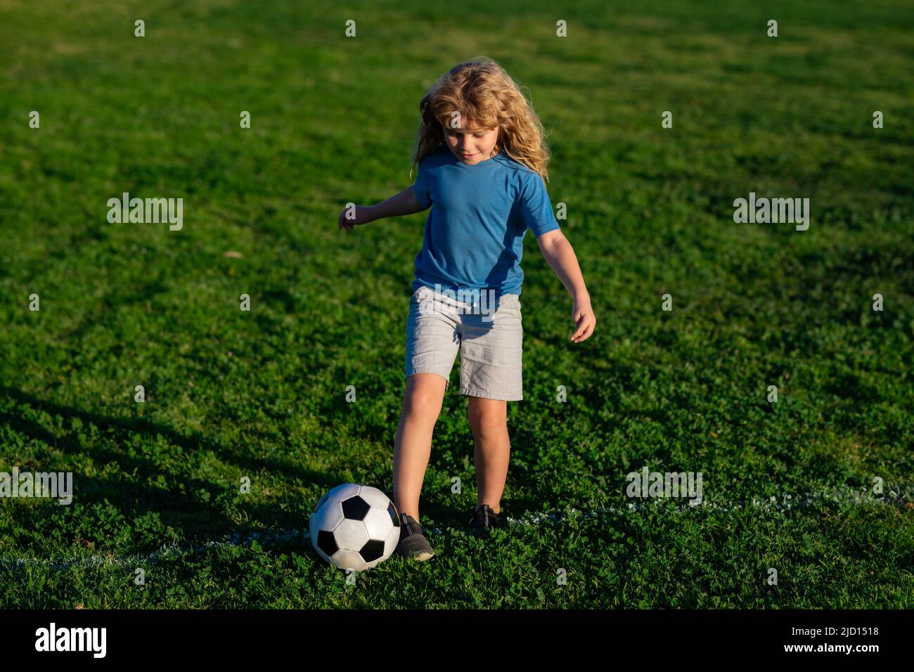 Soccer child play football. Kid kicking a football ball on a grass