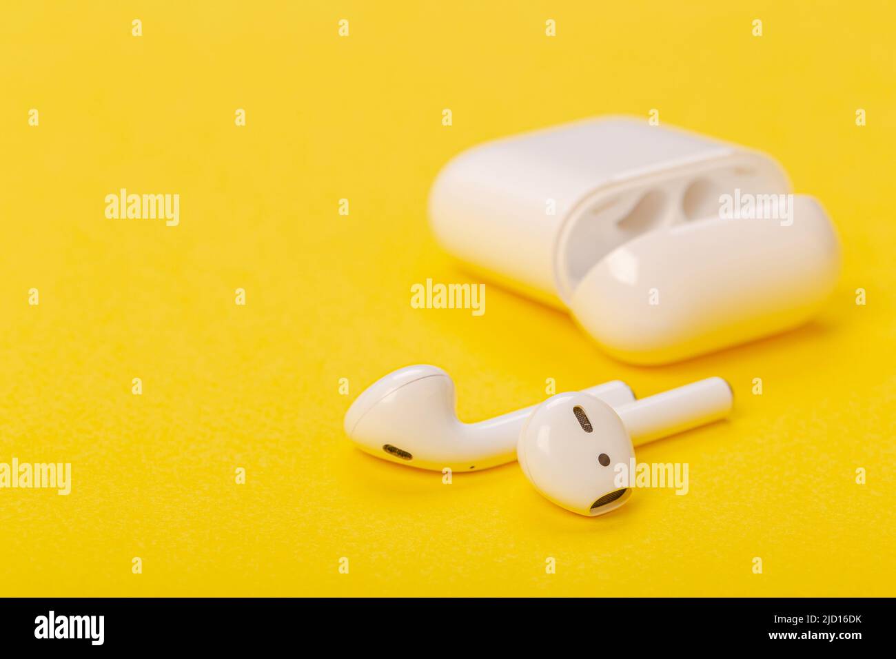 Modern wireless bluetooth headphones with charging case on a yellow