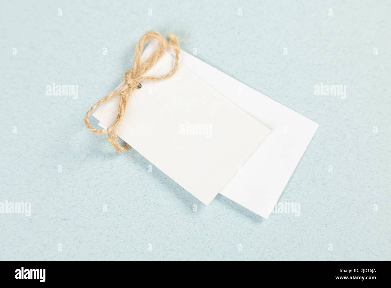 An empty white price tag lies on a gray-blue background with a soft shadow. Stock Photo