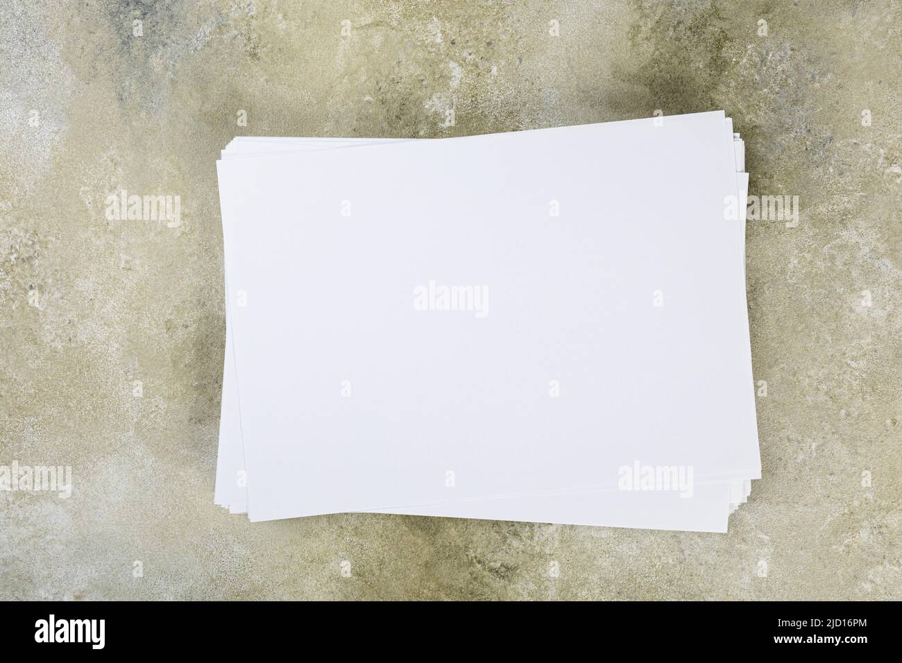 several sheets of paper in a pile of a4 a5 business card on a grunge table. Stock Photo