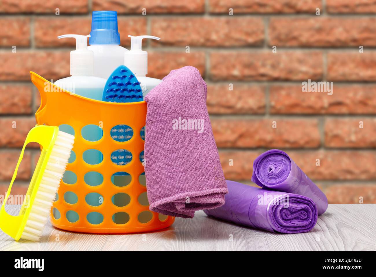 Plastic orange basket with bottles of dishwashing liquid, tile cleaner