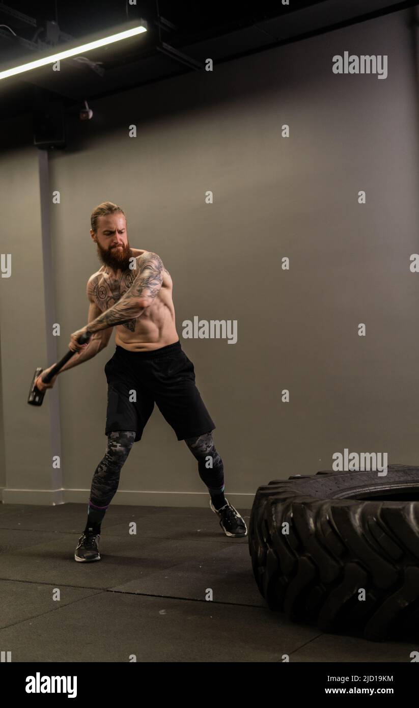 Tire sledge muscular hammer wheel man hitting workout gym exercise