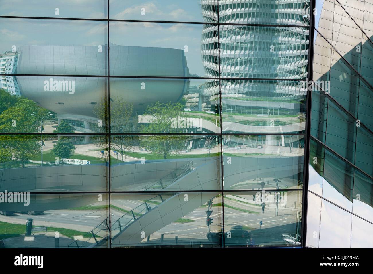 Reflections of the BMW Tower, BMW Museum and Trias Bridge in the glass facade of BMW World Munich, Germany, 9.5.22 Stock Photo