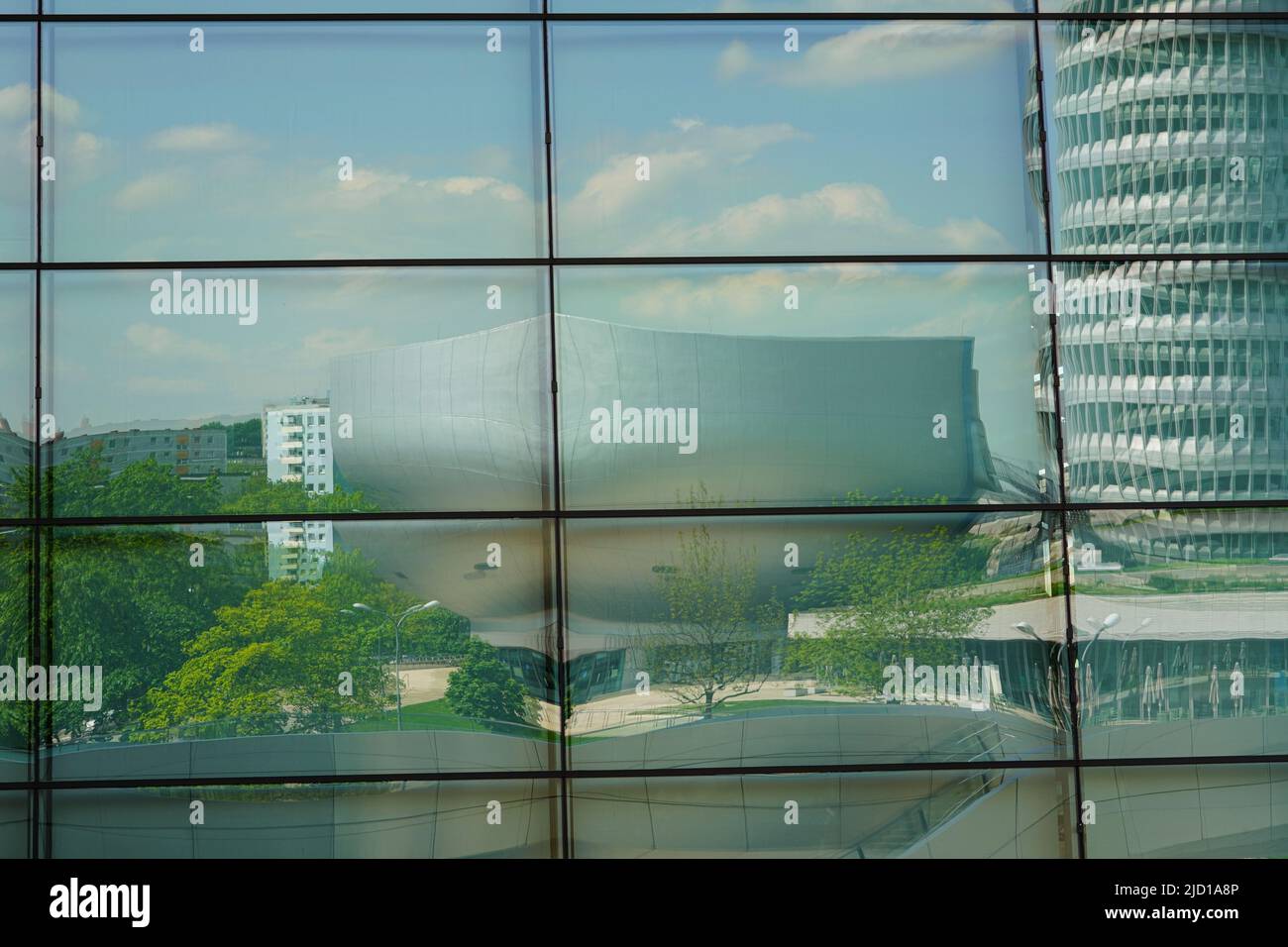 Reflections of the BMW Tower, BMW Museum and Trias Bridge in the glass facade of BMW World Munich, Germany, 9.5.22 Stock Photo