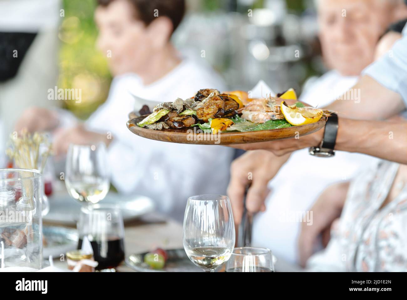 The waiter serves restaurant guests. The waiter holds a tray with food