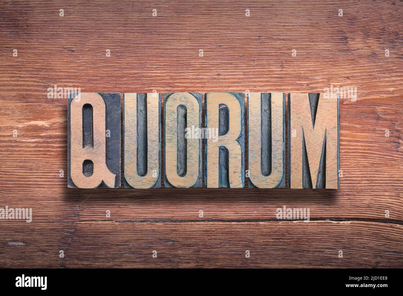 quorum ancient Latin word meaning - of whom; the number of members whose presence is required, combined on vintage varnished wooden surface Stock Photo
