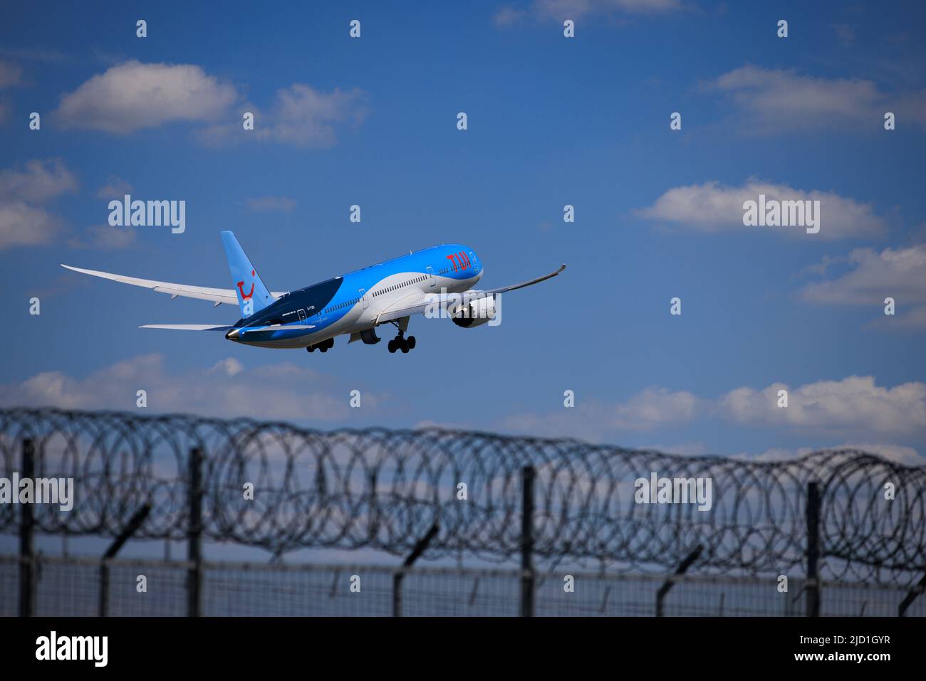 Security fence at Gatwick Airport as a Tui plane takes off on the runway Stock Photo