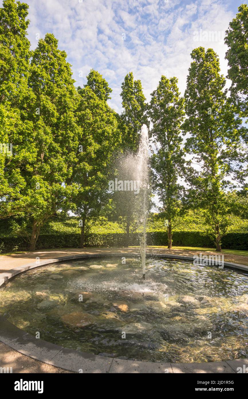 A fountain, surrounded by trees, in the centre of a pond within Alnwick gardens, Northumberland, England, UK Stock Photo