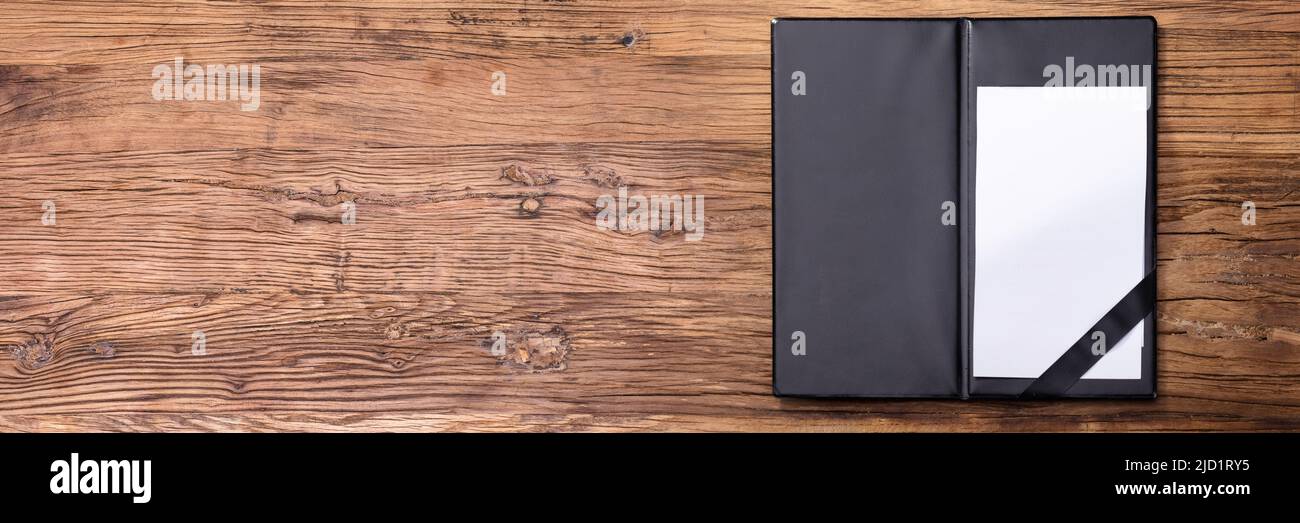 Overhead View Of Blank Empty White Paper In Black Leather Folder On Wooden Table Stock Photo
