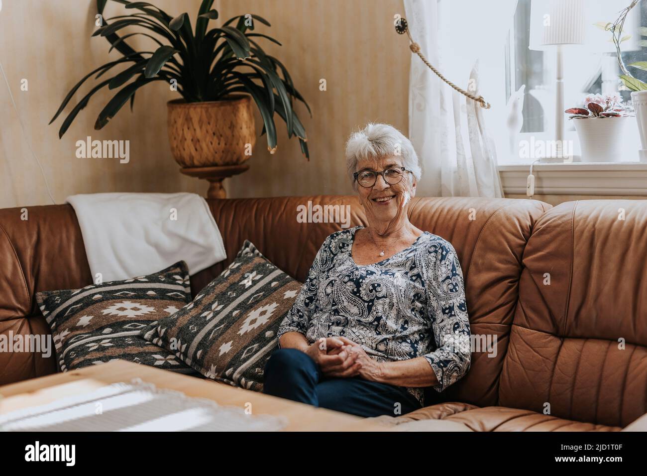 Senior woman sitting on sofa Stock Photo - Alamy