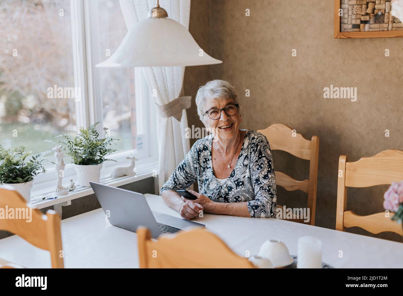 Senior woman sitting at table hi-res stock photography and images - Alamy