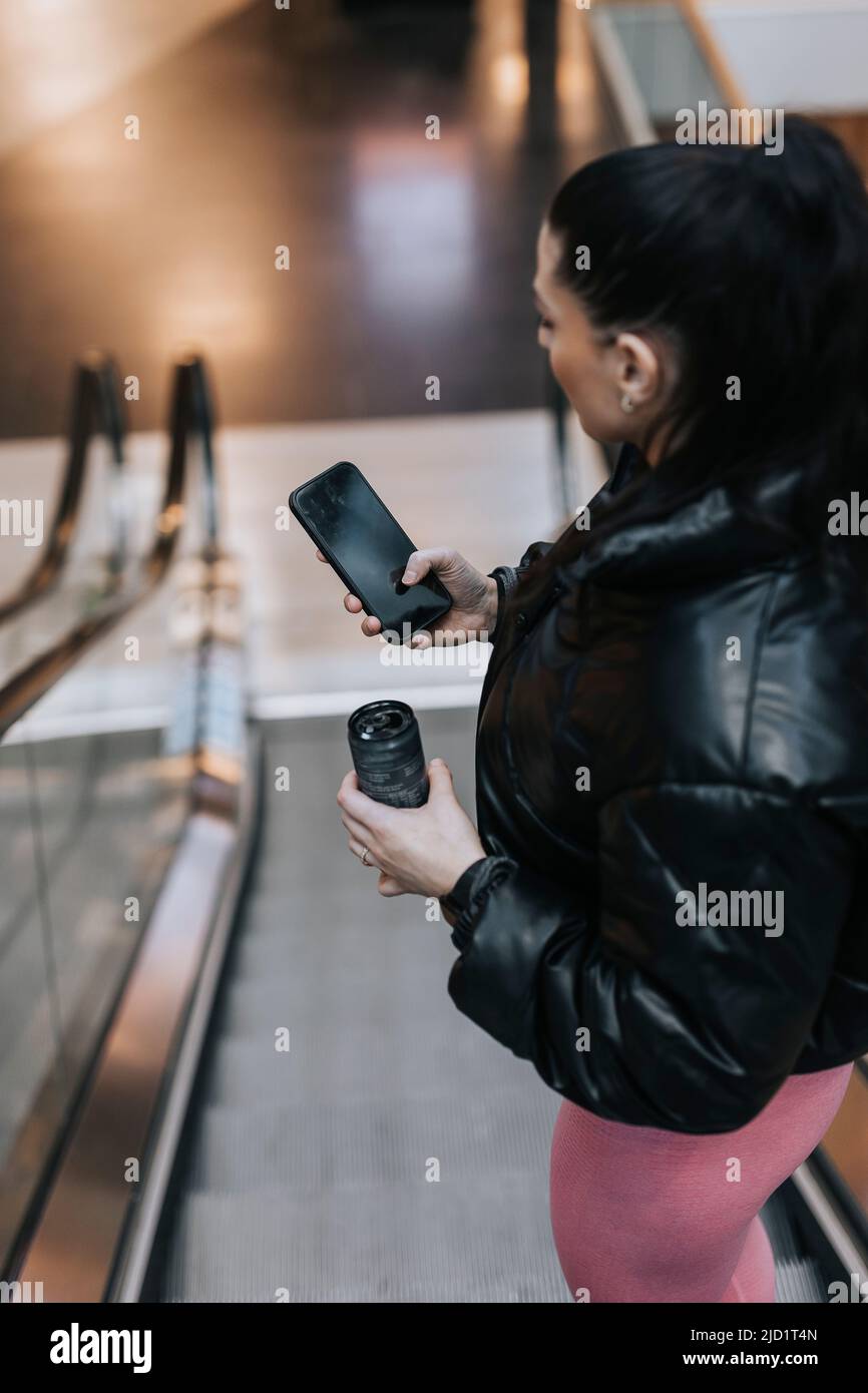 Woman using cell phone at escalator Stock Photo