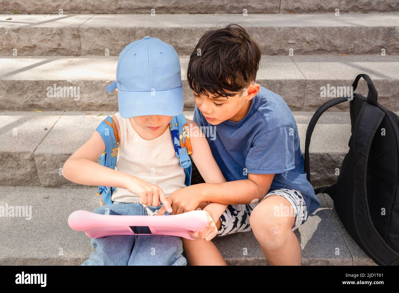 Children sitting on stairs and using tablet Stock Photo