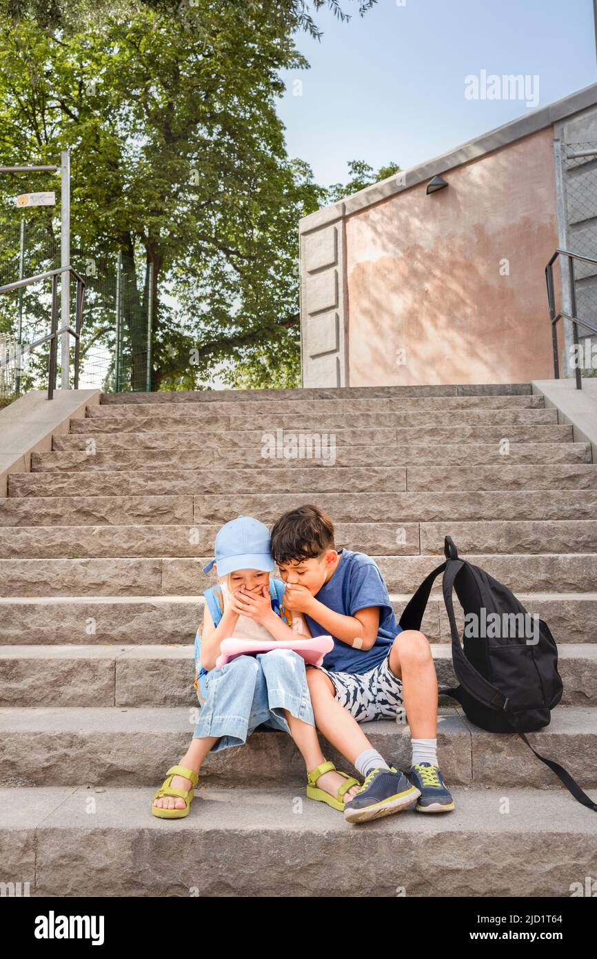 Children sitting on stairs and using tablet Stock Photo
