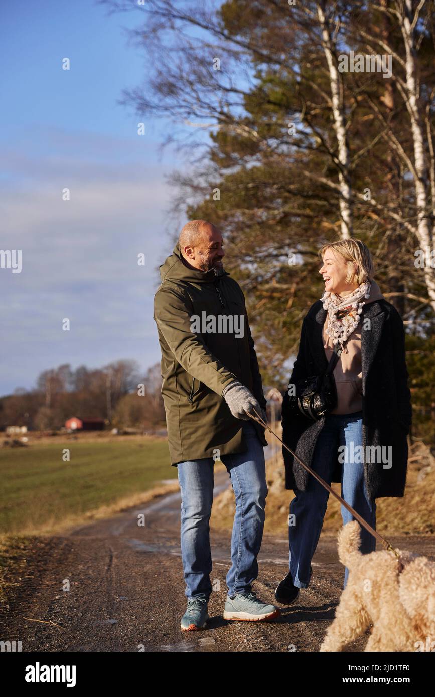 Couple walking with dog Stock Photo - Alamy