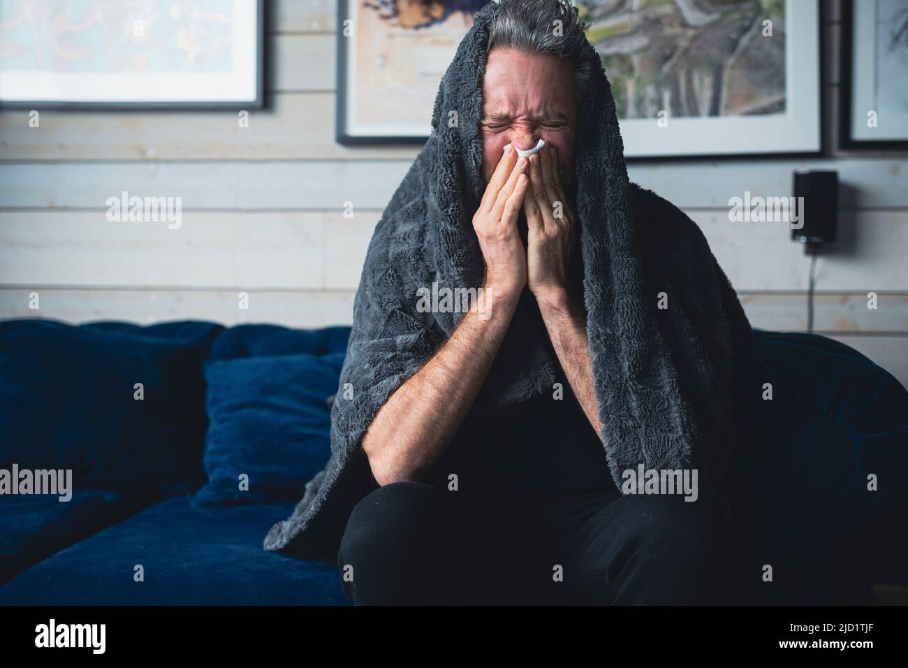 Ill man sitting on sofa Stock Photo
