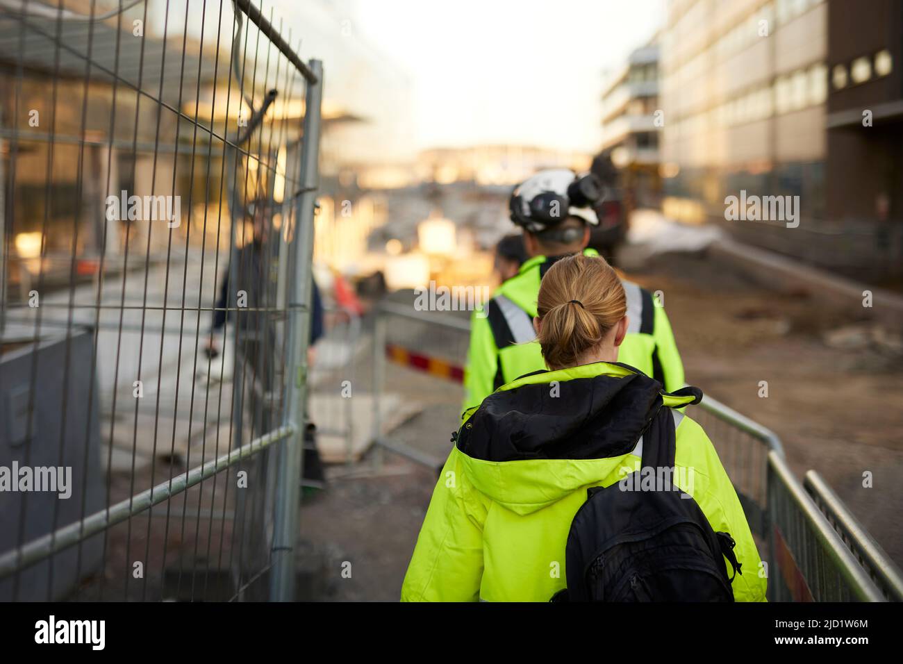 Rear view of two construction workers working at construction site hi ...