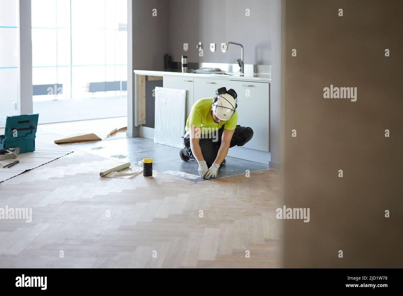 Worker installing floor in kitchen Stock Photo