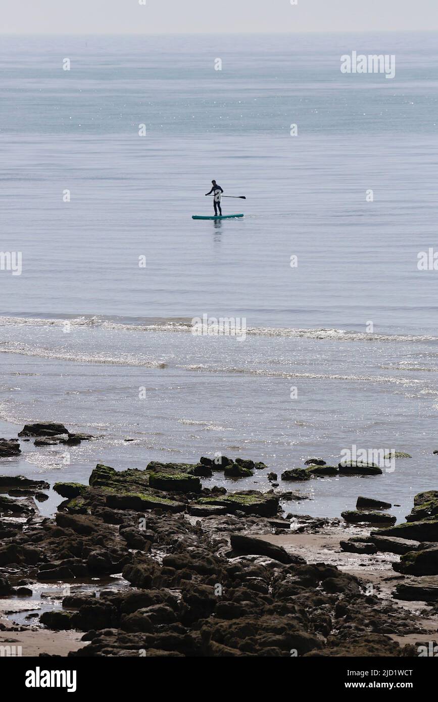 Hastings, East Sussex, UK. 17 Jun, 2022. UK Weather: Very hot and sunny at the seaside town of Hastings in East Sussex as Brits enjoy the very hot weather today that is expected to reach 34c in some parts of the UK. Paddle boarder enjoy the gentle waves this morning. Photo Credit: Paul Lawrenson /Alamy Live News Stock Photo